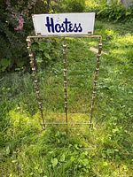 Full front view of vintage Hostess wire chip rack with clip holders and Hostess sign at top, placed on grass.
