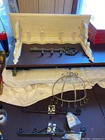 Top view of white wooden shelf with coat hooks, metal key-shaped hanger, metal jewelry hanger with hooks, and two small calendar hangers on the black surface.