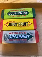 Top view of three closed gum tins showing front vintage Wrigley's branding: Doublemint (green), Juicy Fruit (yellow), Spearmint (silver).