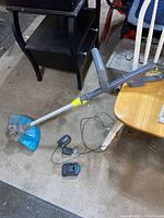 Full view of Yardworks string trimmer leaning against chair showing main body, shaft, and trimming head