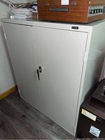 Full view of metal storage cabinet, showing front doors and handle latch.