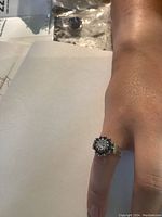 Front view of ring worn on finger showing central diamond cluster and sapphire halo