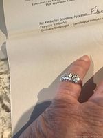 Front view of ring worn on finger showing row of diamonds