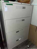 Front view of white metal lateral file cabinet with four drawers and label showing dimensions 36x18x54 inches.