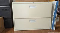 Full front view of beige two-drawer filing cabinet on wooden floor