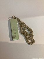 Pendant and chain laid flat showing overall shape and presence of hallmarks