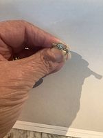 Front view of ring held against white background, showing center diamond and band accent stones