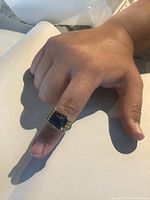 Top view of ring on finger showing rectangular dark blue glass stone and yellow gold bezel