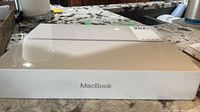 Front view of factory-sealed MacBook box showing MacBook branding