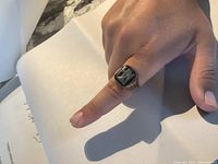 Ring worn on finger showing top view of black onyx and NH initials