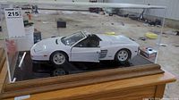 Full view of white Ferrari Testarossa model inside plexiglass case on wooden base