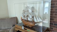 Front view of entire model ship inside clear plexiglass case on wooden base.