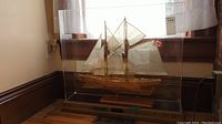 Full view of model ship inside plexiglass case on wooden base