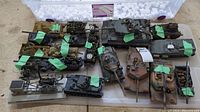 Top view of all 19 military vehicle models arranged in a plastic tote with some green tape on models to secure loose or damaged parts.