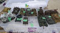 Wide view of 13 assorted model tanks arranged on top of plastic containers with packing peanuts around them.