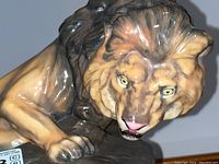 Close up of the lion's head and front paws showing detailed painting and facial expression.