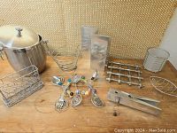 Full lot view showing stainless steel ice bucket, wire baskets, napkin holder, trivets, tongs and decorative fork set