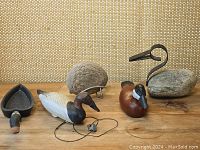 Full view of two hand-painted wooden duck decoys, abstract stone and wrought iron duck sculpture, and an additional decorative rock.