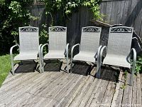 Front view of four identical greige outdoor chairs arranged side by side on a deck