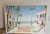 Front view of the framed painting showing the complete Palm Beach scene with houses, palm trees, and ocean.