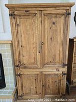 Front view of rustic Mexican pine armoire showing two upper and two lower closed doors with iron hinges and natural wood grain.