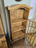 Front view of rustic pine bookcase showing three open shelf sections and two pull-out drawers at bottom, arched top design.