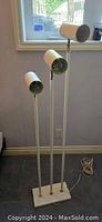Full view of the vintage 3-light floor lamp showing the three white cylindrical light heads and rectangular base.
