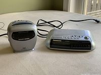 Side by side photo of two clock radios; Philips on left, Panasonic on right. Both plugged with power cords visible.