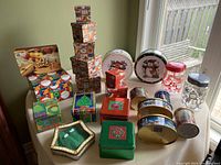 Photo shows assortment of Christmas themed gift boxes, tins and plastic containers on a table