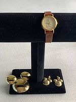 Photo of gold-tone Mickey Mouse brooch, matching earrings, and Lorus Quartz watch with brown leather strap