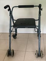 Front angled view of blue walker showing seat and padded handle bars.