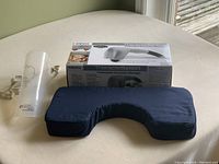 Homedics percussion massager in box and blue neck support pillow on bed