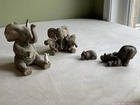 Five elephant figurines posed on a light surface, showing size and grouping.