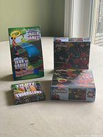 Overview of four items: two Spider-Man puzzles with 100 pieces each, Crayola tie-dye chalk sticks box, Crayola Chalk Games Bean Bag Toss game box. Items are new.
