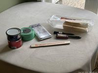 Photo showing entire painter's lot including paint can, painter's tapes, paintbrushes, paint stirrers, and packaged wall border kit.