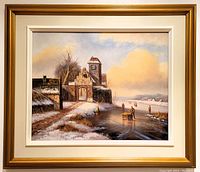 Framed oil on canvas winter landscape painting with ice skaters and rustic stone buildings under a cloudy sky; gold painted wood frame and cream inner border visible.