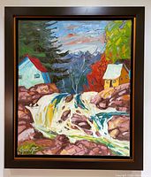 Front view of framed painting showing autumn landscape with waterfall, houses, pine trees in black wood float frame with gold inner liner