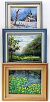 Three framed original landscape oil paintings displayed stacked vertically: winter cabin scene, green mountain valley, and yellow flowers pond.