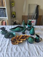 Photo showing entire lot of nine Blue Mountain Pottery and Beauceware items arranged on a white tablecloth including vases, owl figurine, swan dish, leaf-shaped dish, sugar bowl, and creamer pitcher.