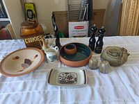 Wide shot of all items in lot showing variety of ceramic pieces including chip and dip bowl, tray, cookie jar, pitchers, salt and pepper shakers, figurines, and stoneware.