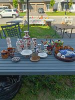Full view of all Chinoiserie lot items arranged on outdoor table including vases, figurines, cups, and fish teapot