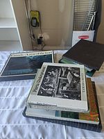 Photo showing a stack of seven coffee table books on various subjects including Canada, Britain, and Paris Underground.