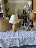 Five lamps on a table featuring vintage and modern styles, some with shades and some without.