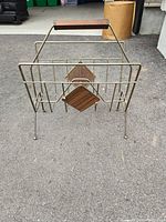 Front view of the MCM brass and wood magazine rack showing its geometric design and wooden accents.