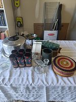 Overview of the lot showing tiki glasses, cake tin, lidded basket, and various kitchen and decorative items arranged on a table.