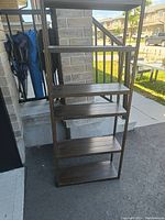 Full view of the metal shelf unit showing the five shelves and metal frame in an outdoor setting.