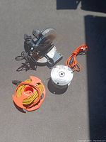 Overview photo showing mitre saw, yellow extension cord on orange plastic spool, orange power cord, and a metal extension cord spool with brown cord.