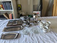 Full overview of servingware lot including trays, condiment holder, glass bowls, ceramic cups, and stainless steel coffee pot.