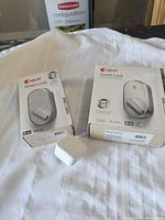 Two boxed August Smart Locks and one loose white Wi-Fi bridge device on white cloth.