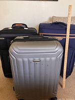 Set of four luggage pieces arranged with a measuring stick against a wall for scale, showing sizes and style variety.